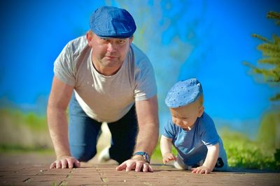 A father and son ,  same color berets and walking on all fours a father teaches his son to crawl blu