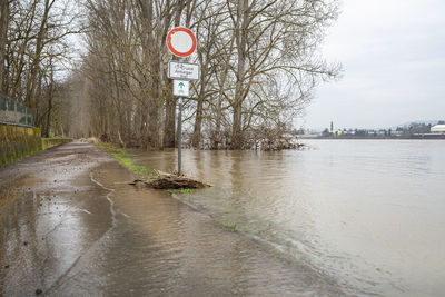 Road sign by river against sky