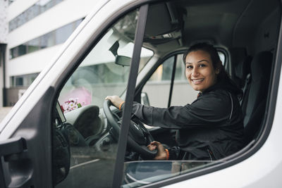 Portrait of smiling woman driving delivery van in city