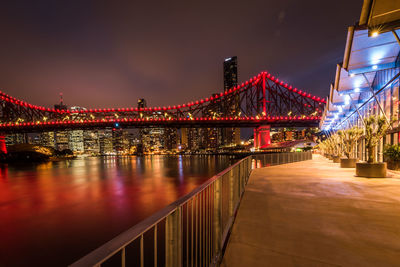 Illuminated bridge over river at night