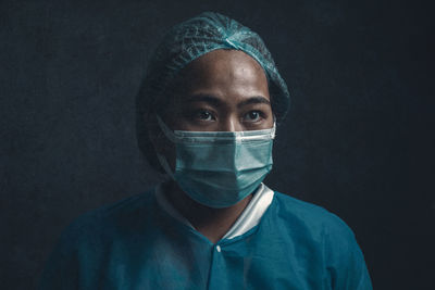 Portrait of man wearing hat against black background