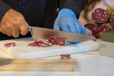 Butcher cutting sausage slices with large knife