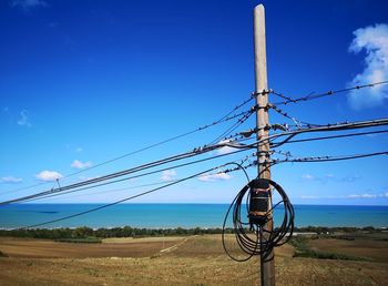 Electricity pylon on field against sky