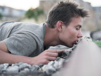 Young man lying on gravels by railroad track