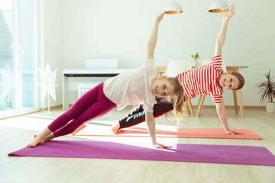 Full length of girls exercising at home