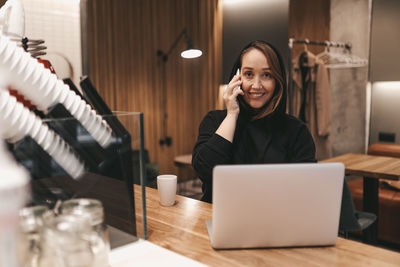 Adult confident business woman freelancer working in a coffee shop cafe using a laptop and phone