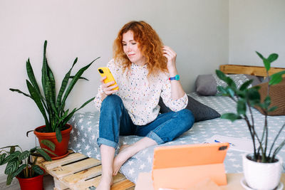 Portrait of young woman sitting on table at home