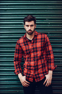 Portrait of young man standing against wall