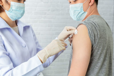 Doctor wearing mask vaccinating patient in clinic