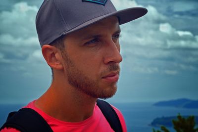 Close-up of young man looking away against sky