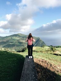 Rear view of woman standing on mountain against sky