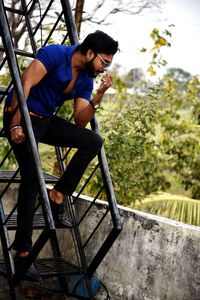 Full length of young man sitting on slide at playground