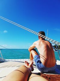 Couple sitting on yacht against clear sky