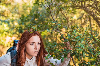 Young woman looking away by plant