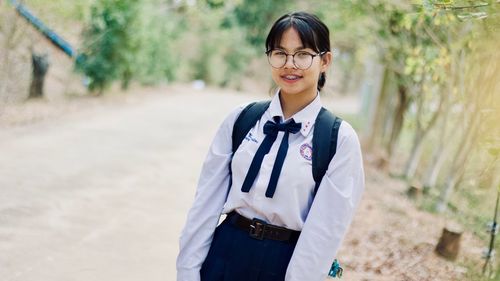 Portrait of smiling young woman standing on road