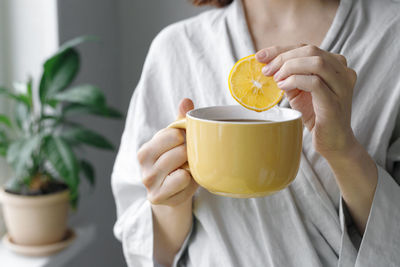 Midsection of woman holding lemon tree at home