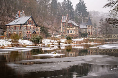 Buildings by lake during winter