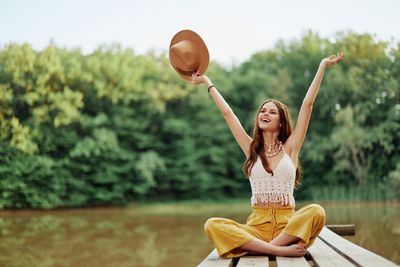 Portrait of young woman holding basketball while standing against trees