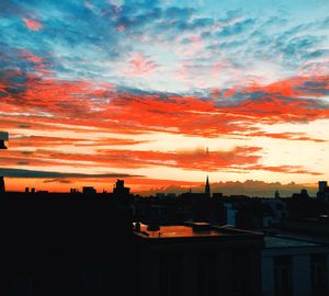 Silhouette cityscape against dramatic sky during sunset