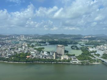 Aerial view of buildings by sea against sky