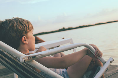 Small boy relaxing on a pier at sunset.