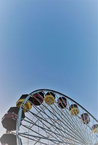 Low angle view of ferris wheel against clear blue sky