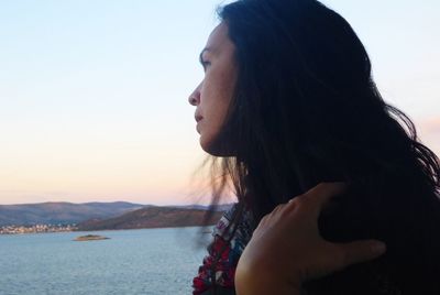 Side view of mid adult woman by sea against sky