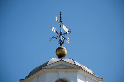Low angle view of weather vane on tower against clear blue sky