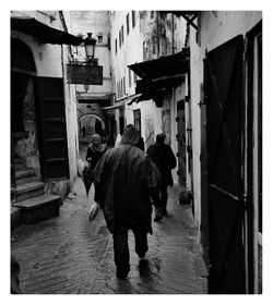 Rear view of people walking on street amidst buildings