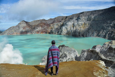 Rear view of man looking at sea against mountains