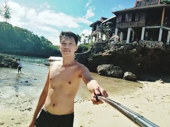 Full length of shirtless boy standing at beach