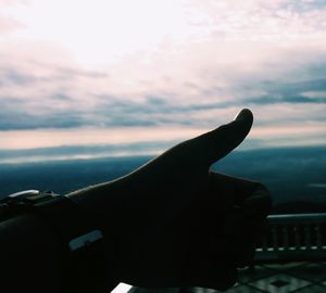 Close-up of hand against sky during sunset