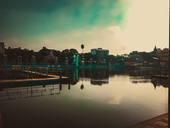 River by buildings against sky during sunset