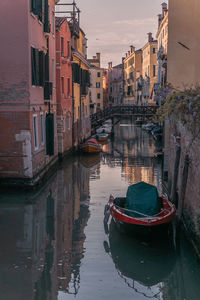 Boats moored in canal amidst buildings in city