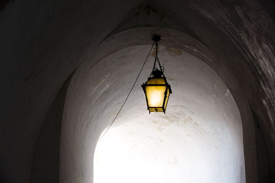 Low angle view of illuminated pendant light hanging in building