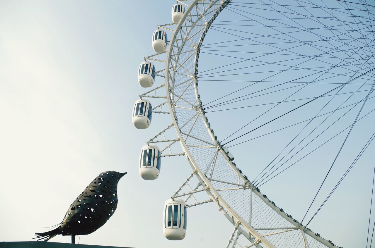 low angle view, arts culture and entertainment, amusement park, ferris wheel, amusement park ride, enjoyment, fun, sky, day, outdoors, fairground, power line, city life, vacations, fairground ride, carefree, no people, adventure