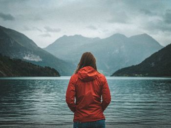 Rear view of man looking at lake against mountain range