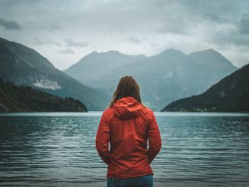 Rear view of woman looking at lake against mountains