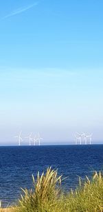 Wind turbines on sea against sky