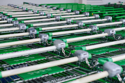 Many empty green shopping carts in row. row of parked trolleys in supermarket.