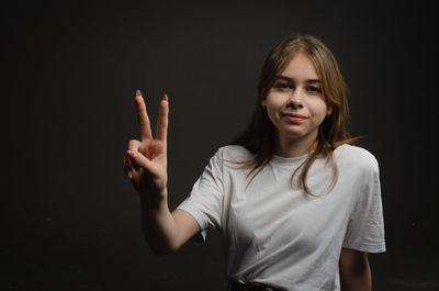 Portrait of young woman against black background