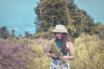 Woman wearing hat standing against plants