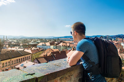 Young man looking at cityscape against sky