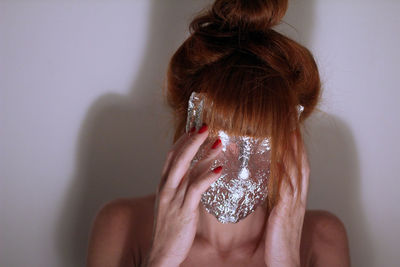 Close-up of woman covering face against white background