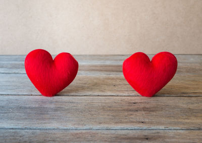 Close-up of red heart shape decoration on wood against white background