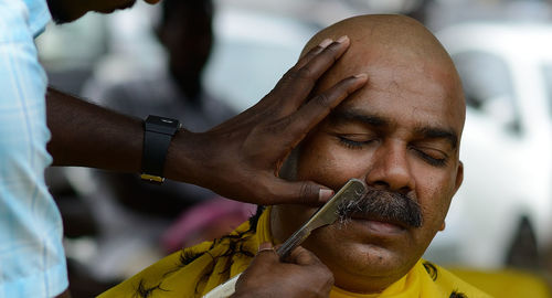 Cropped image of barber shaving mustache of customer