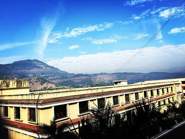 mountain, mountain range, sky, built structure, architecture, building exterior, cloud - sky, cloud, railing, house, blue, transportation, nature, day, beauty in nature, scenics, residential structure, sunlight, town, residential building