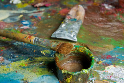 Close-up of paintbrush and messy paints