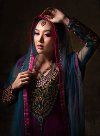 Portrait of beautiful young woman standing against black background