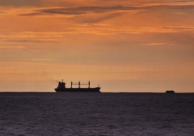 Silhouette boat sailing on sea against sky during sunset
